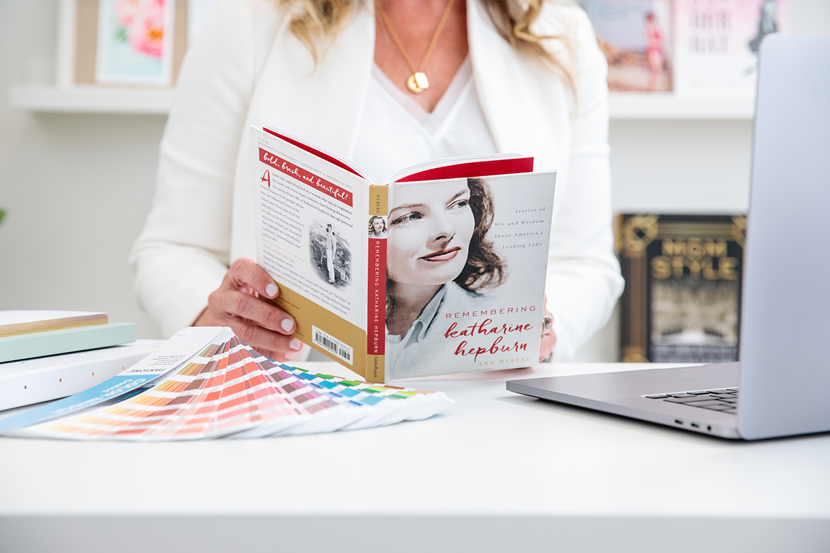 Jen Huppert sitting at her desk reviewing the book cover and interior design that she created for Remembering Katharine Hepburn.